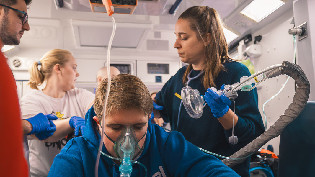 Teilnehmende versorgen im Rettungswagen einen Patienten mit Sauerstoffmaske