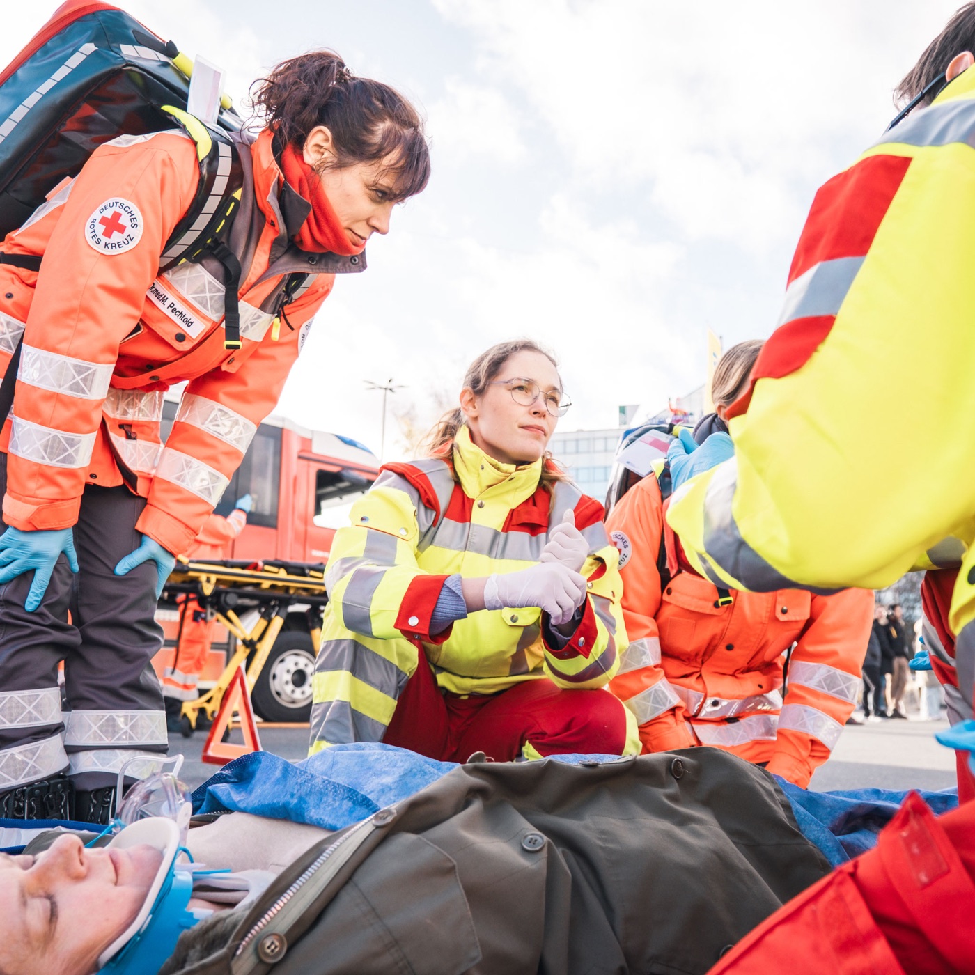Teilnehmende in Rettungsdienstkleidung versorgen bei einer Übung eine am Boden liegende Person