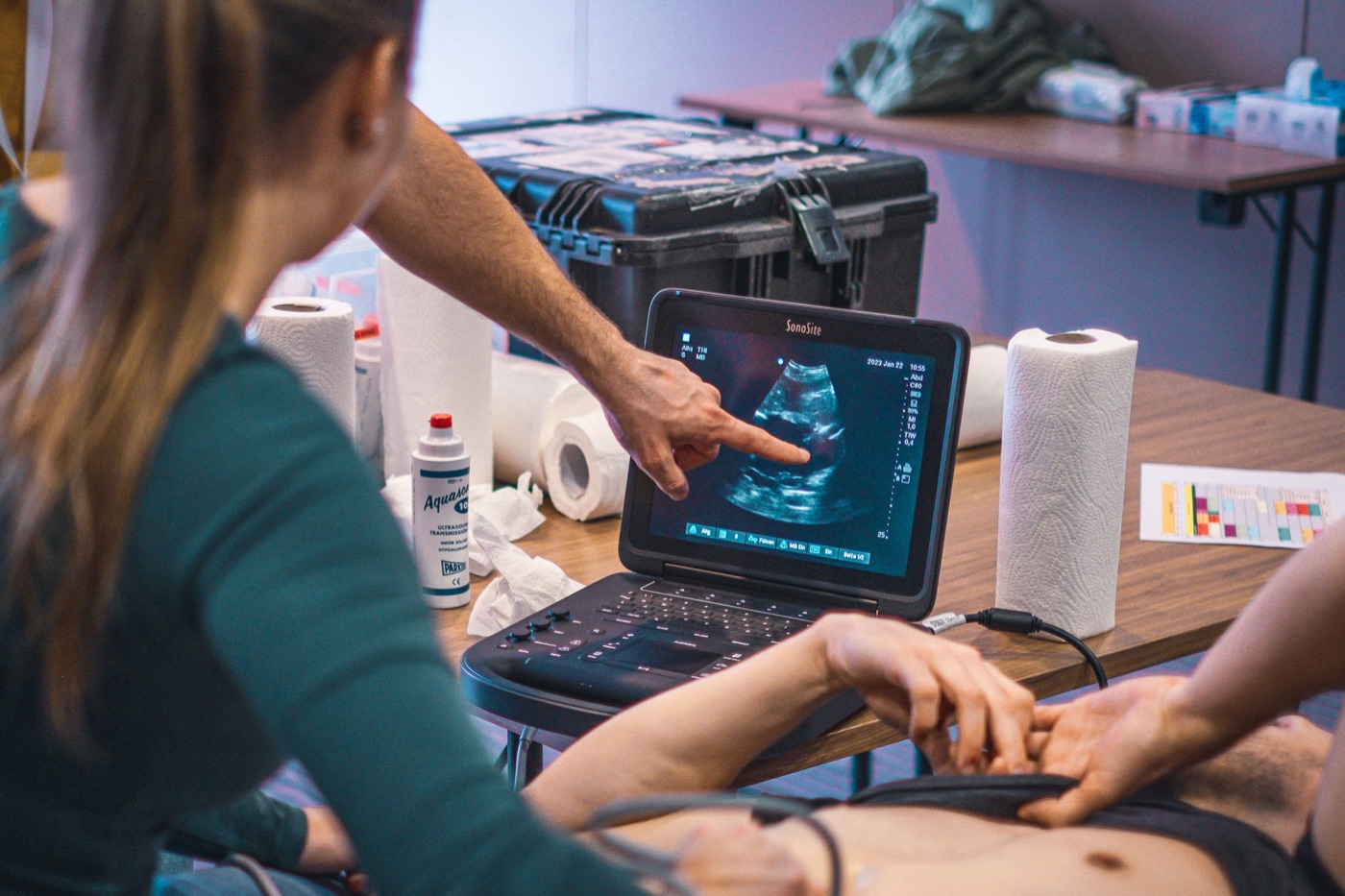 Sonografie-Training: Eine Teilnehmerin führt eine Ultraschalluntersuchung durch, das Bild erscheint auf einem Laptop