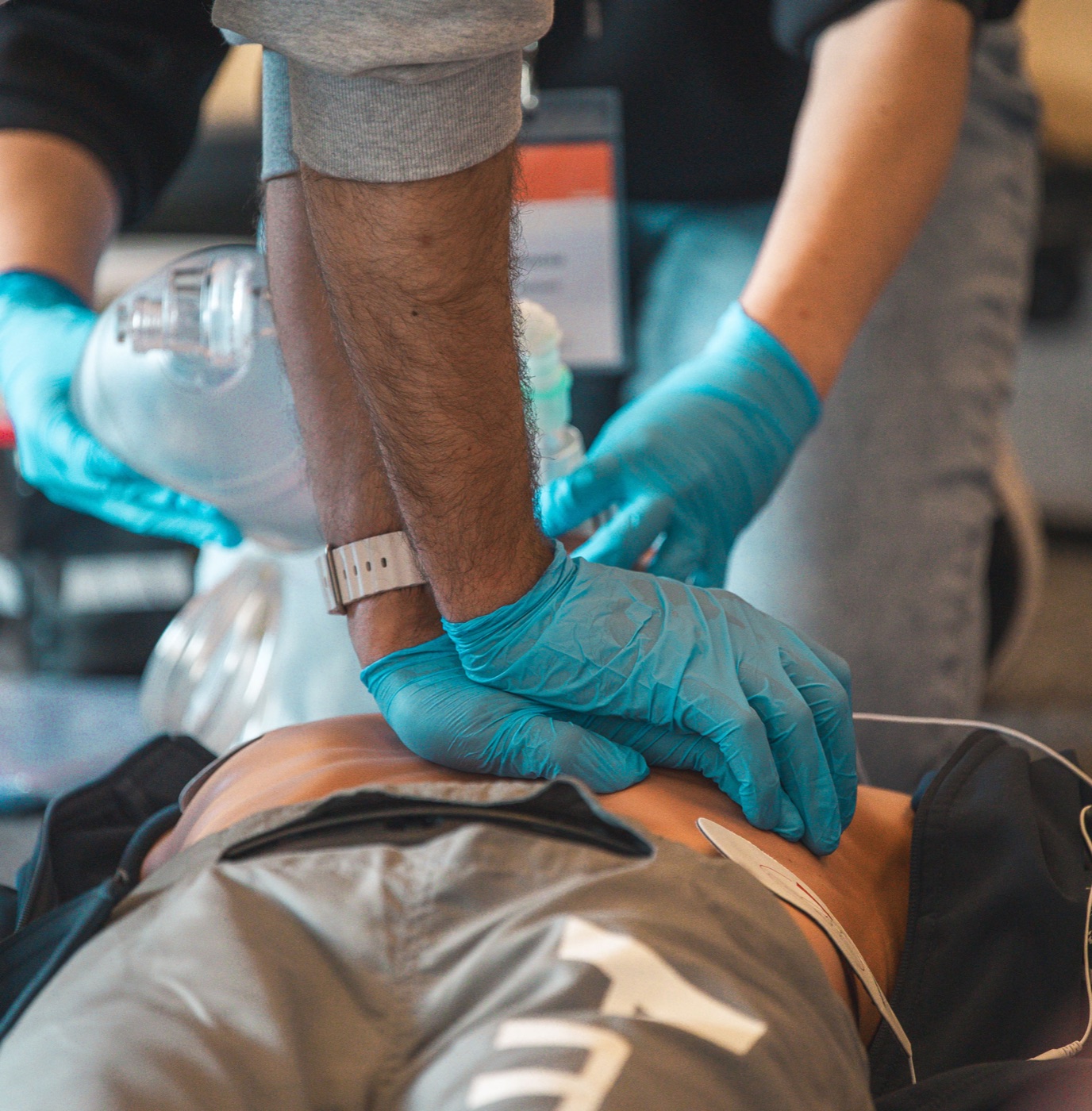 Ein Teilnehmer übt die Herzdruckmassage an einer Simulationspuppe, daneben wird beatmet