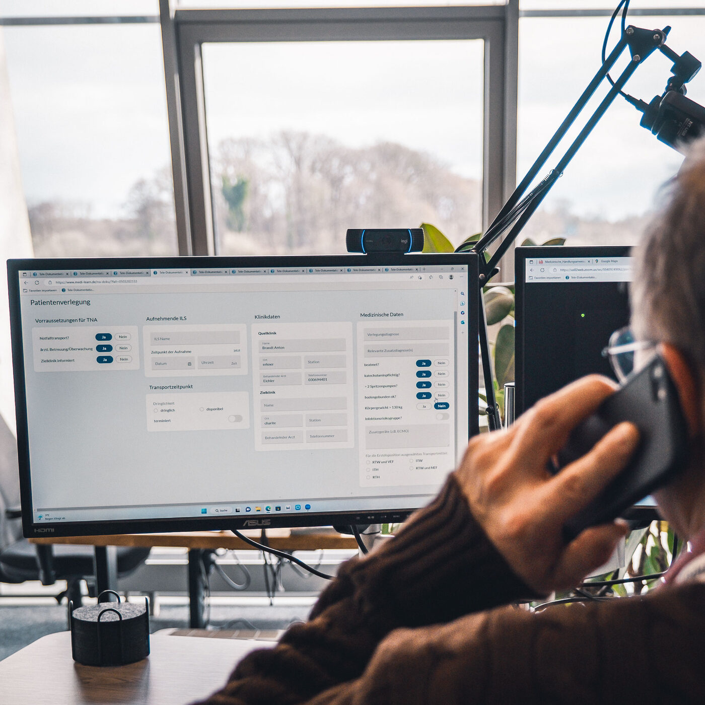 Ein Teilnehmer telefoniert am Telenotarzt-Arbeitsplatz, vor ihm mehrere Monitore