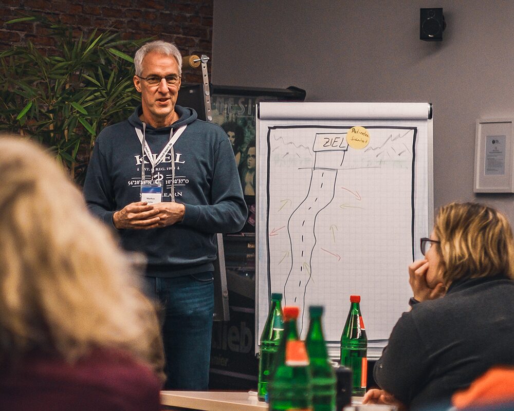 Ein Dozent erklärt am Flipchart, Teilnehmende hören zu