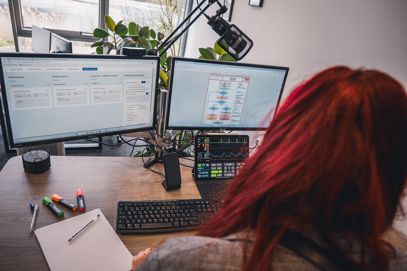 Eine Teilnehmerin arbeitet am Telenotarzt-Arbeitsplatz mit Headset und zwei Monitoren